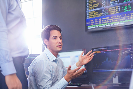 male office worker in front of finance screens