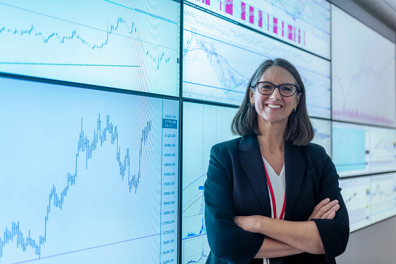 woman standing in front of lots of screens with financial data