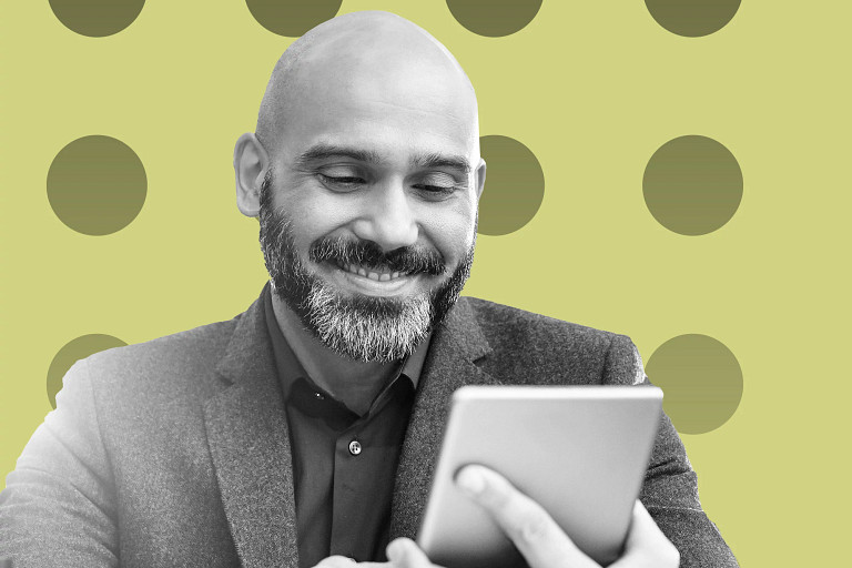 Black-and-white image of a person in a blazer holding and looking at a tablet device, shown from the chest up, set against a light green background with evenly spaced circular patterns.