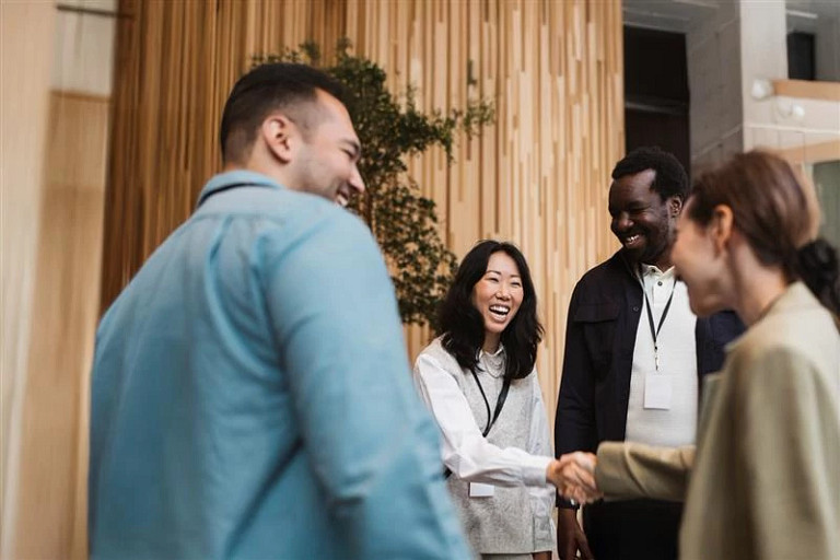 Happy female entrepreneur doing handshake with young delegate during seminar at convention center