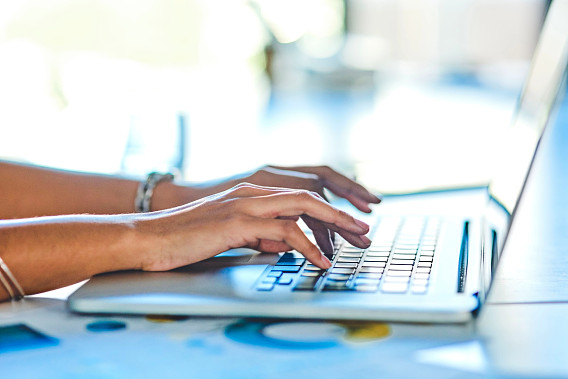 Hands typing on a laptop