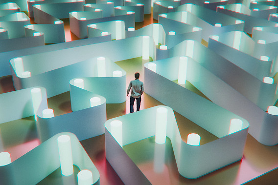 A man stands at the entrance of a glowing, futuristic maze made of tall, curved walls illuminated in blue and pink light, symbolizing confusion or decision-making.