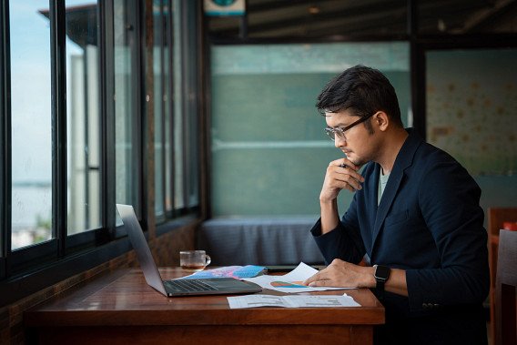 Asian young businessman working with laptop at office, office worker browsing in laptop for necessary information.